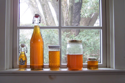 Glass jars and bottles filled with maple syrup on a windowsill.