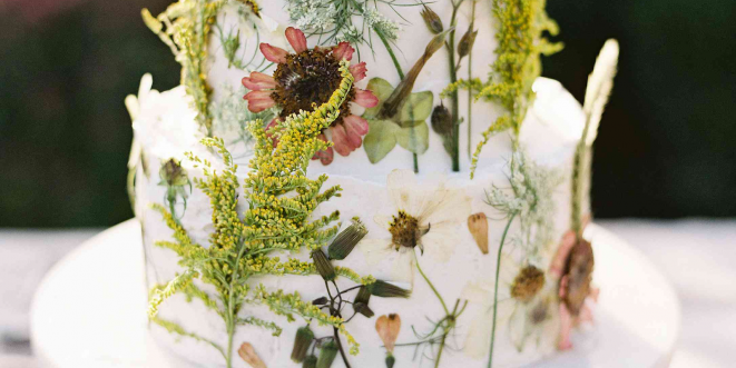 Close-up of a white wedding cake decorated with various flowers.