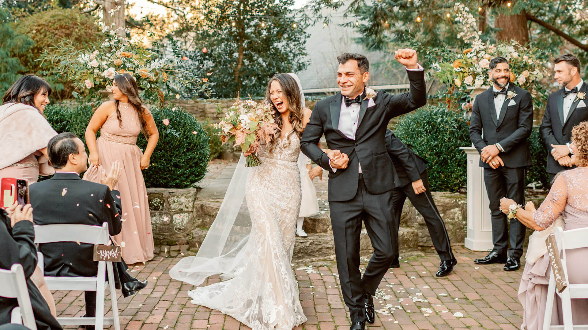 Bride and groom happily holding hands and walking back down the aisle, surrounded by guests.